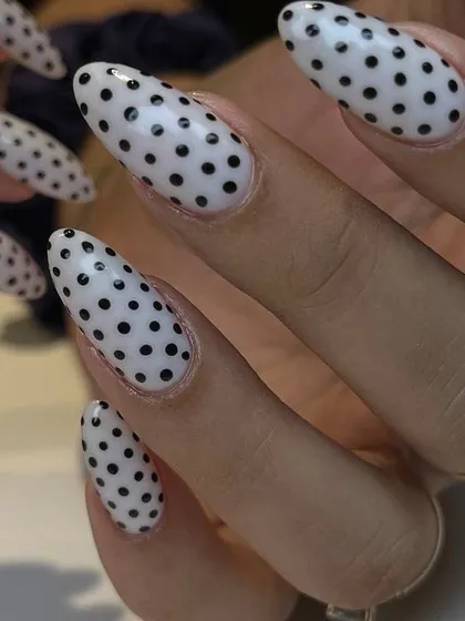 A classic and fun black and white polka dot design on long, almond-shaped nails. This timeless pattern is always a stylish choice.