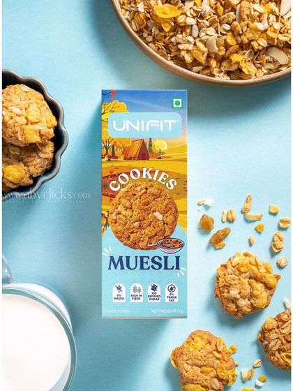 A Unifit muesli cookie box, shot against a light blue background with muesli and milk.