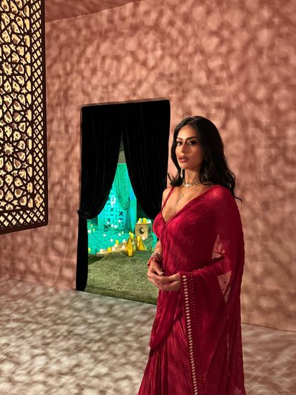 The soft lighting and intricate shadows add a magical quality to this portrait in the red saree.