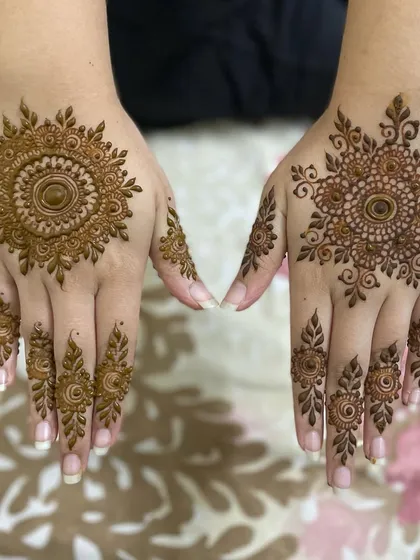 A beautiful example of two different mandala styles. One hand has a classic sun-like mandala, while the other features a more floral and intricate version.