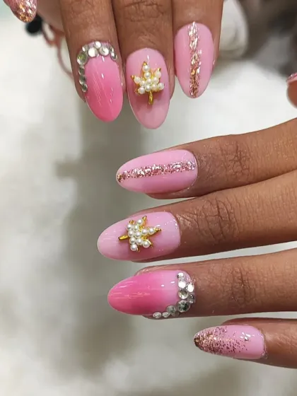 A close-up view of the 3D charms and crystal work on the pink bridal nails, showing the dimension and texture of the design.