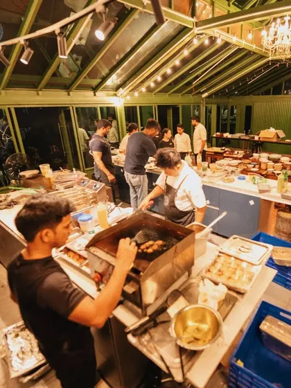 A behind-the-scenes view of our bustling kitchen setup for an event. This wide shot shows the teamwork and organized chaos required to execute a large-scale, high-quality catering service.