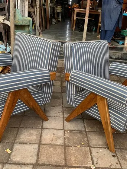 These Pierre Jeanneret inspired lounge chairs feature a bold striped fabric and cylindrical armrests. The solid teak V-leg frame provides a sturdy and stylish base, showing how different upholstery can completely change the character of a classic design.