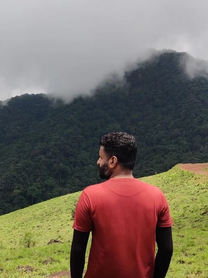 A trekker looking out at the misty mountains from the Kodachadri trail.