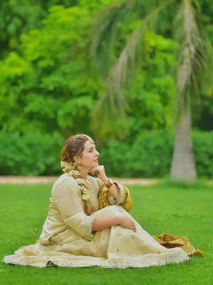 A thoughtful, candid moment captured on the grass. This relaxed pose in a full lehenga shows that traditional wear can be comfortable and natural, not just for formal occasions.