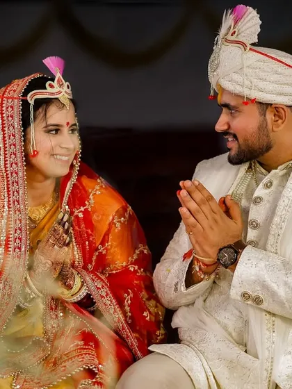 A beautiful, candid moment during the wedding ceremony. The groom's gesture of 'namaste' towards his bride is a sign of respect and love, captured in the warm glow of the sacred fire.