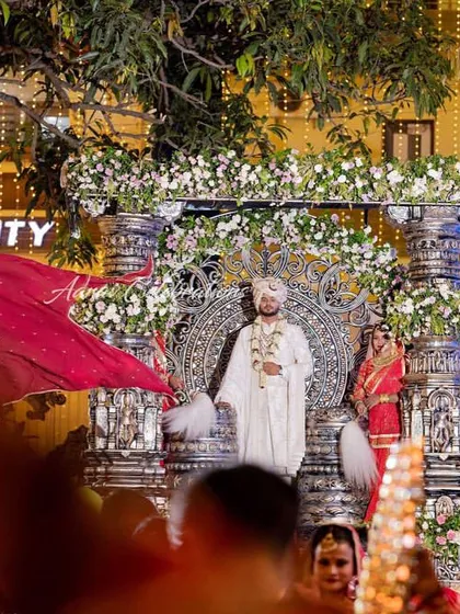 The groom stands majestically on his silver chariot, surrounded by a crowd of guests and performers. This view from the crowd shows the impressive scale and impact of such an entry.