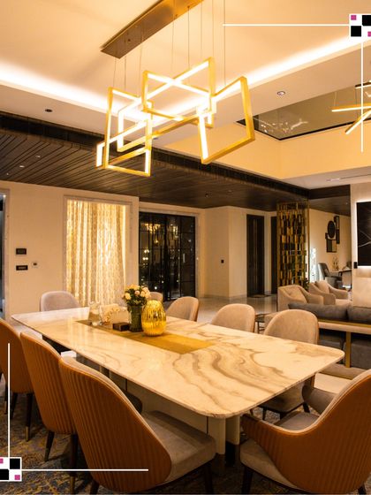 A long, elegant dining table set under a modern, geometric chandelier. This space is designed for large family gatherings, with comfortable seating and a sophisticated ambiance.