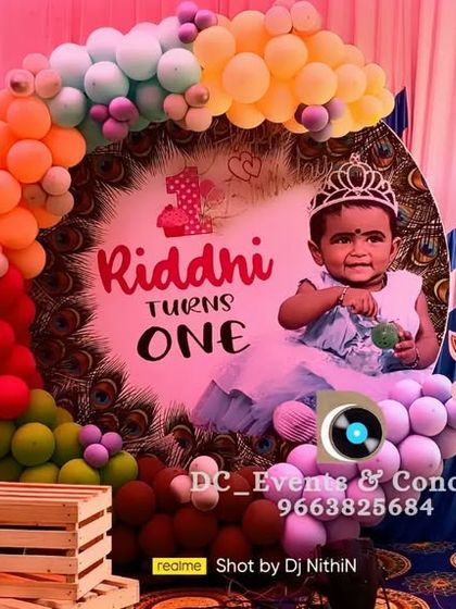 A cute animal-themed first birthday party. This setup includes a custom photo backdrop, a colorful balloon arch, and adorable cutouts of a panda and giraffe, perfect for a child's celebration.