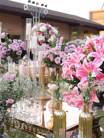 An elaborate floral and candle arrangement. The mix of pink lilies, baby's breath, and tall candles creates a stunning and romantic centerpiece.
