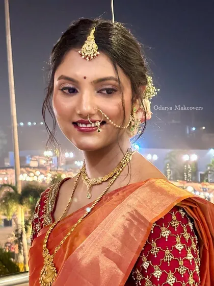 Drenched in tradition and love. This look features a warm, glowing makeup palette that perfectly complements the orange and red tones of her beautiful silk saree and gold jewellery.