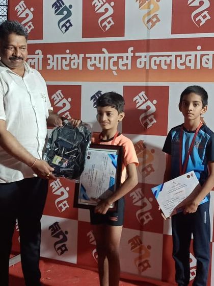 An official presents Swaransh with his prize after winning the gold medal at the 1st Aarambha competition. He earned a new backpack and certificate for his outstanding performance.