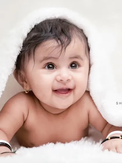 A three-month-old baby girl with the most heart-melting smile. We love capturing these simple, beautiful portraits on a soft white background.
