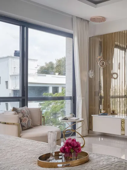 This reading nook is all about luxurious comfort. A curved accent chair with a brass frame is paired with a delicate side table, creating an ideal spot to relax by the window.