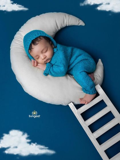 A close-up of our moon and stars theme. This angle highlights the cozy knit outfit and the peaceful slumber of the newborn, creating a truly magical image.