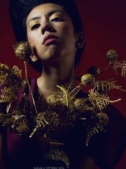 A high-fashion concept featuring bold, gold glitter eyeshadow and matching metallic props. This kind of textural and avant-garde makeup is perfect for making a statement in magazine editorials.