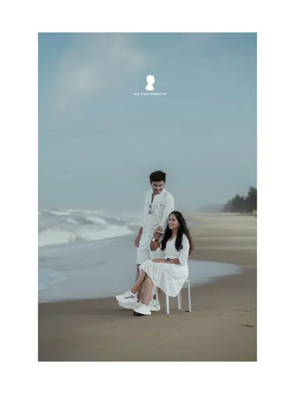 A serene beach pre-wedding shoot. The couple, dressed in white, creates a clean and classic look against the backdrop of the sea and sand.
