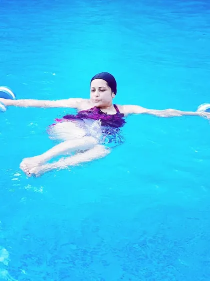 A member holds a pose while floating with dumbbells. This exercise requires core control and builds stability, showcasing a more advanced move in our aqua fitness program.