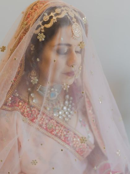 A serene bridal portrait, with the bride's face partially covered by her delicate veil. An image of grace and beauty.