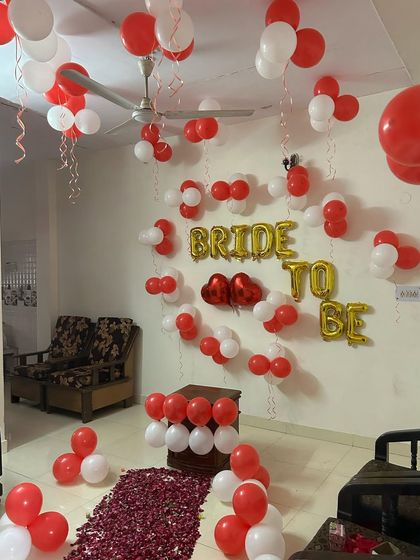 A simple yet beautiful 'Bride to be' setup in red and white. This decor is perfect for an intimate home party, featuring foil letter balloons, heart-shaped accents, and a romantic rose petal walkway. (Also shown in images 49, 50, 51).