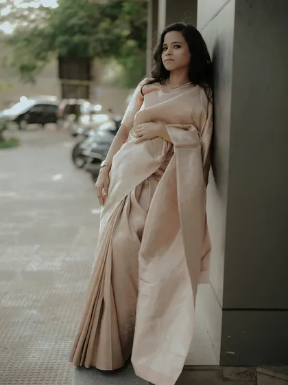 A stylish, full-length portrait against a modern, urban backdrop, highlighting the timeless beauty of the saree.