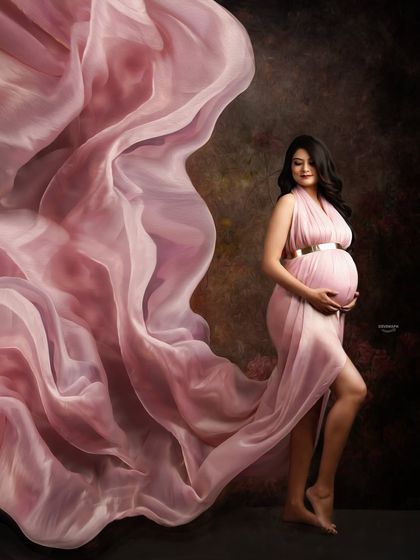 Capturing movement and elegance, this shot features a sheer pink gown with fabric tossed to create a beautiful, flowing effect. The dark, moody background makes the subject pop.