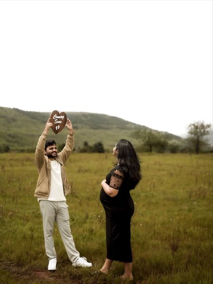 A celebratory shot of the dad-to-be joyfully lifting the "Coming Soon" sign against the open sky. It’s a photo full of energy and excitement for the adventure ahead.