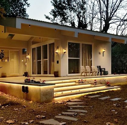 Another view of the Amberle farmhouse, where the illuminated steps create a floating effect over the lawn. This design detail adds a touch of modern elegance to the rustic setting.