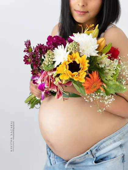 A close-up on the beautiful bump, adorned with a vibrant bouquet of flowers. This shot focuses on the life and color of pregnancy, a truly incredible time.