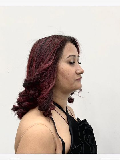 A side profile of the curly red hairstyle, highlighting the volume and texture created by the curls and the richness of the color.