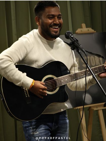 A guitarist and singer with a huge smile, loving the vibe at our open mic.