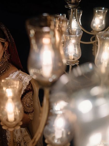 An artistic shot of the bride, her face partially hidden by a chandelier, creating a soft and dreamy effect.