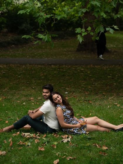 A peaceful and relaxed moment in a London park. The couple sits back-to-back on the grass, creating a serene and connected portrait away from the city bustle.