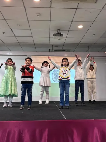Students strike a pose at the finale of their patriotic dance performance, their arms raised in a gesture of strength and unity.
