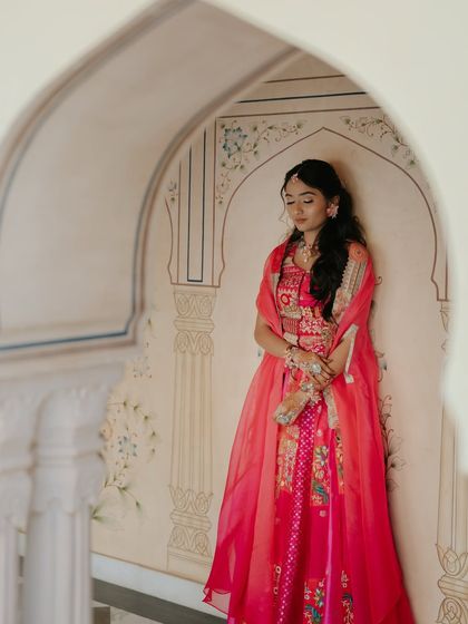 A full-length shot showing how the simple, wavy hairstyle complements the vibrant and detailed bridal outfit without overwhelming it.