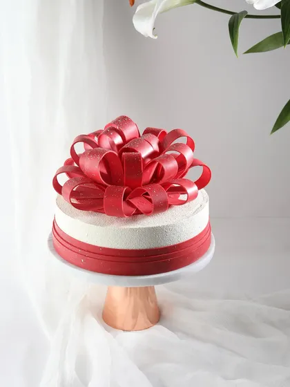A gift of love. This stunning cake is topped with an intricate, edible red chocolate bow, making it the perfect centerpiece for a romantic celebration.