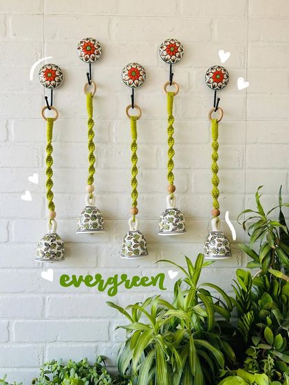 Our 'Evergreen' macrame ceramic bells, shown here in a set of five. The vibrant green cotton cords and hand-painted bells are perfect for adding a touch of nature to your home decor.
