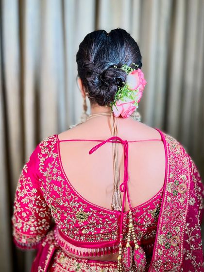 A detailed shot of the bridal bun, adorned with fresh pink roses. A classic hairstyle that adds a touch of romance and elegance to any bridal look.