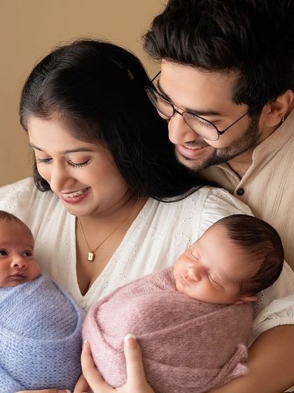 A beautiful family portrait with their newborn twins, one sleeping and one awake.