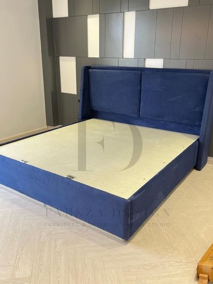 A custom-made bed in a deep royal blue. The winged, two-panel headboard offers a classic silhouette, providing a touch of timeless style to the bedroom.