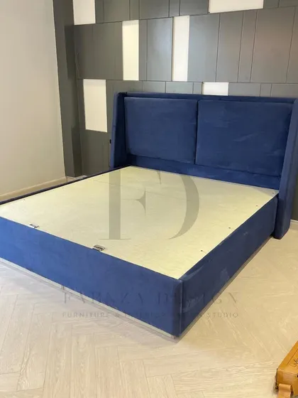 A custom-made bed in a deep royal blue. The winged, two-panel headboard offers a classic silhouette, providing a touch of timeless style to the bedroom.