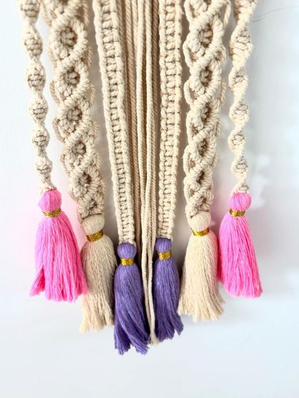 Detail shot of the beautiful pink, purple, and cream tassels that add a playful touch to the 'Mitanshi' wall hanging.