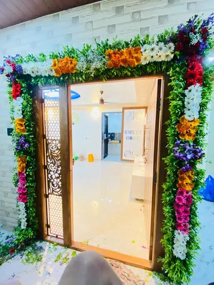 A lush and colorful floral frame around the main door of a home for a housewarming or festive event.