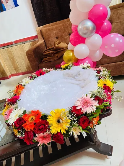 A close-up of the welcome baby cradle, beautifully decorated with a ring of fresh, colorful flowers.