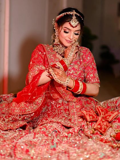 A classic bridal pose, with the bride looking down at her hands, highlighting her henna and bangles.
