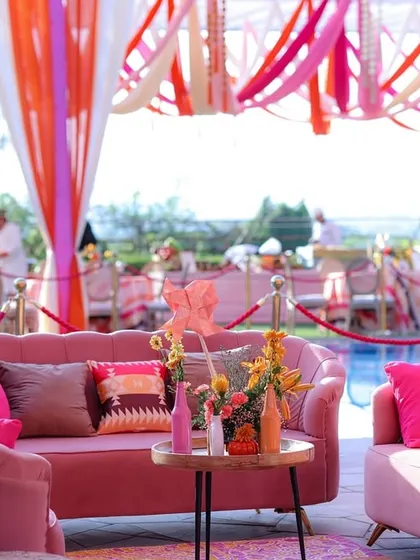 The vibrant pink sofas and colorful cushions create a cheerful and inviting atmosphere for the high-tea event.