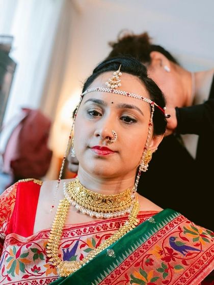 A candid shot of a bride during her hair and makeup session. Our team works together to ensure every detail of the traditional bridal look is perfect before the ceremony begins.