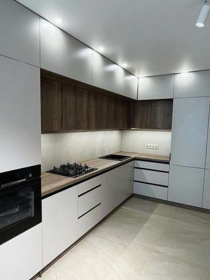 This perspective highlights the integrated tall unit and the dual hob setup (gas and induction). The layout is designed for a practical and efficient cooking experience.