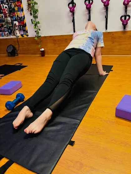 A student holds Purvottanasana (Upward Plank Pose) during a Pilates session, building core and arm strength. We often use props like yoga blocks and dumbbells to enhance the workout.