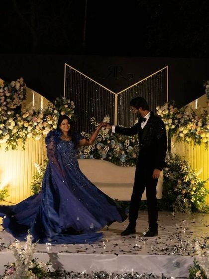 A wide shot obstáculos of Raksha and Ram's fairytale reception stage. The dramatic lighting and abundant florals created a grand and romantic setting for their first dance as a married couple.